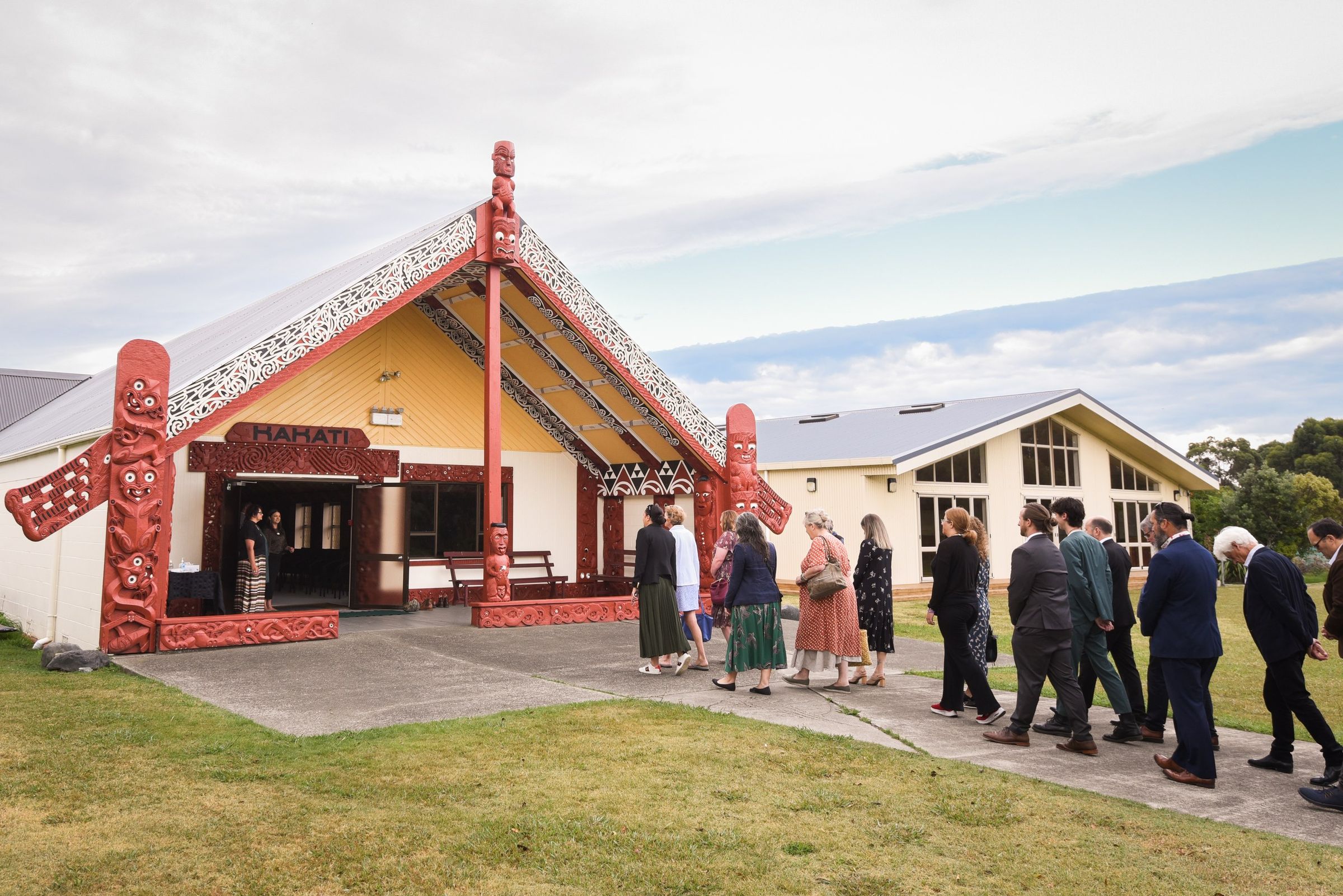 Manuhiri walking towards the carved entrance of Kahati wharenui