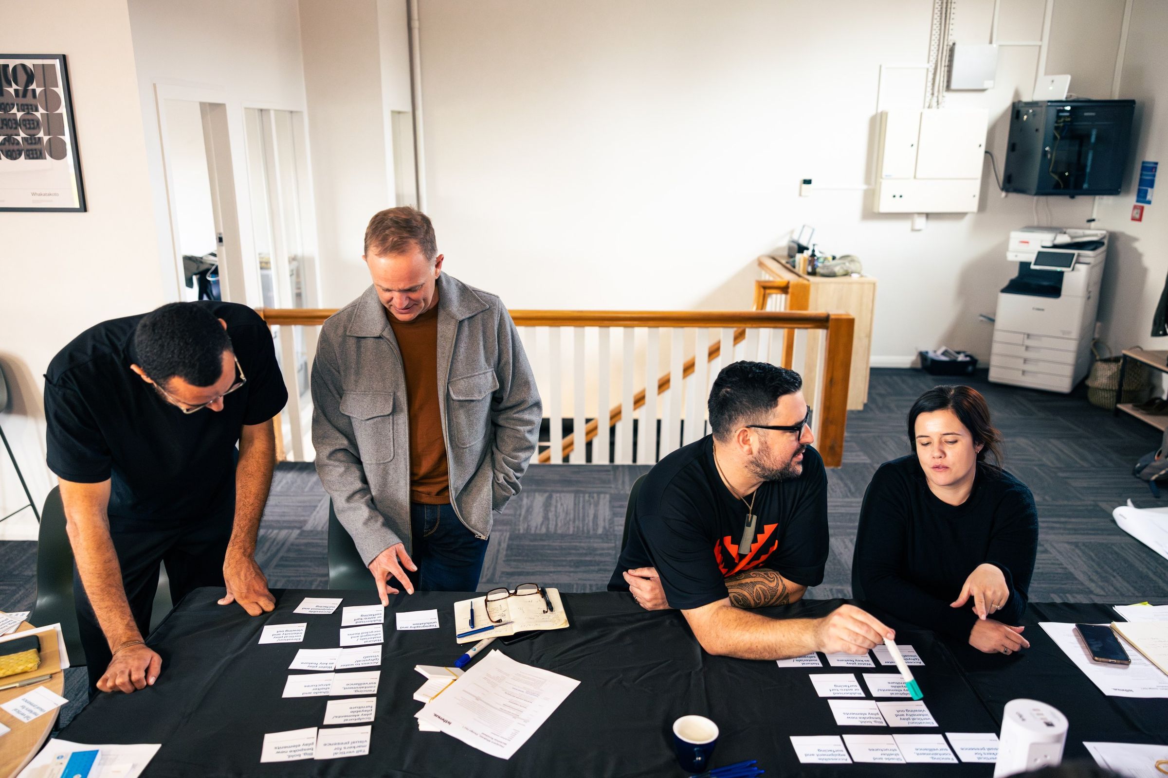 Four people standing over a table of option cards, mid-discussion