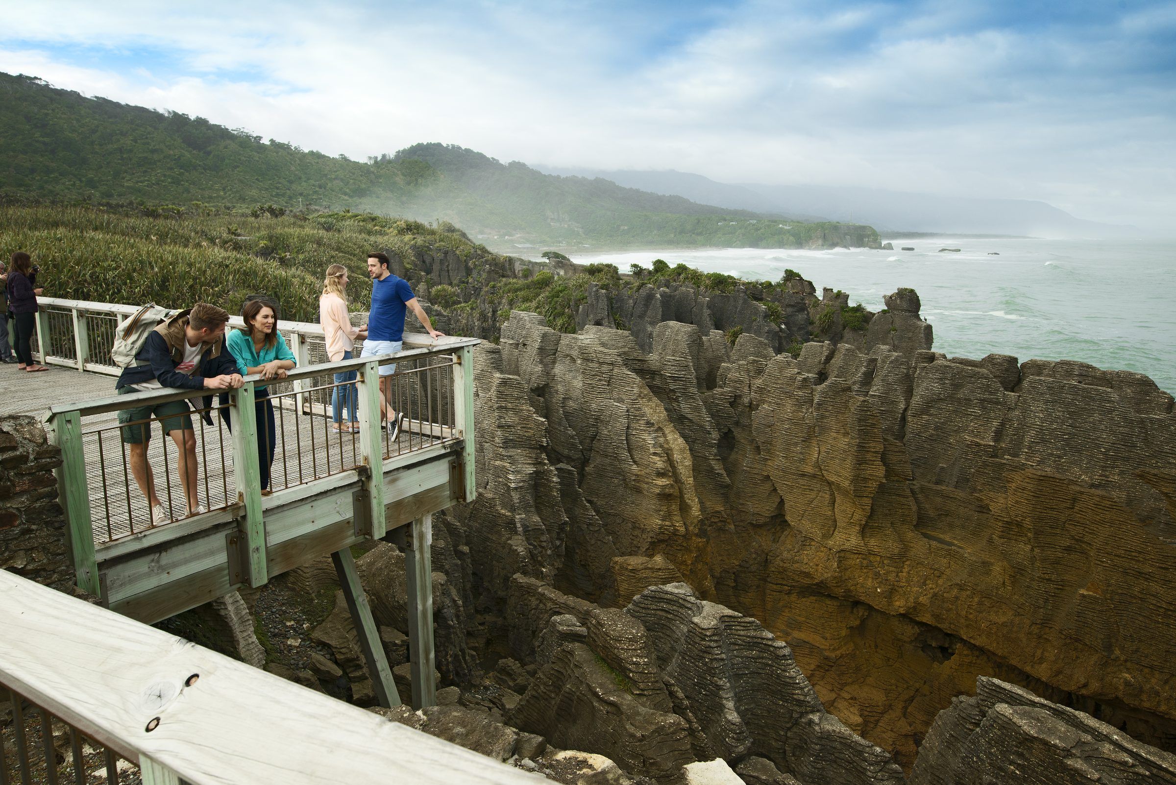 Visitors on a lookout above the layered rocks at Punakaiki