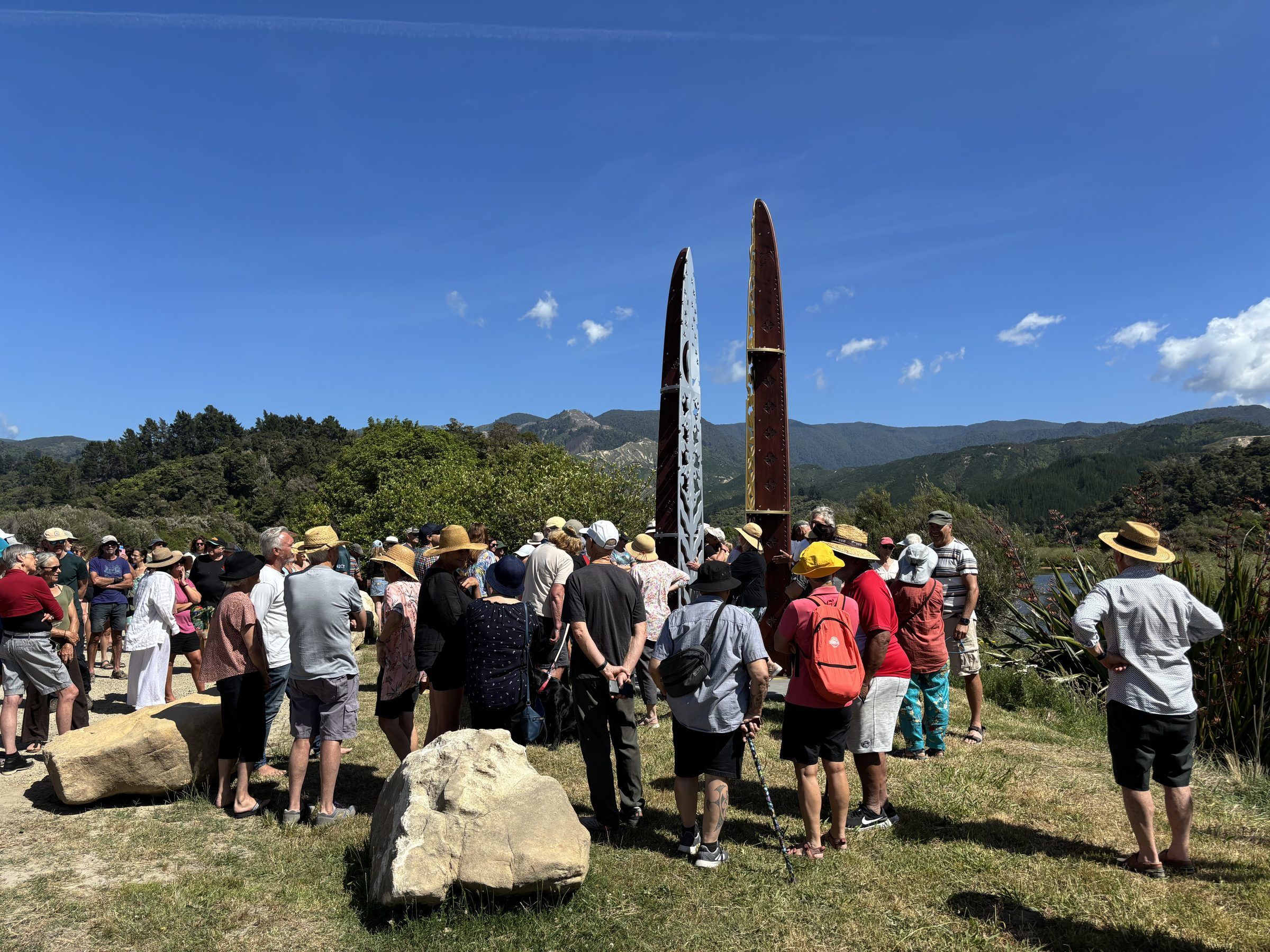 A crowd gathers around a newly unveiled carved public artwork