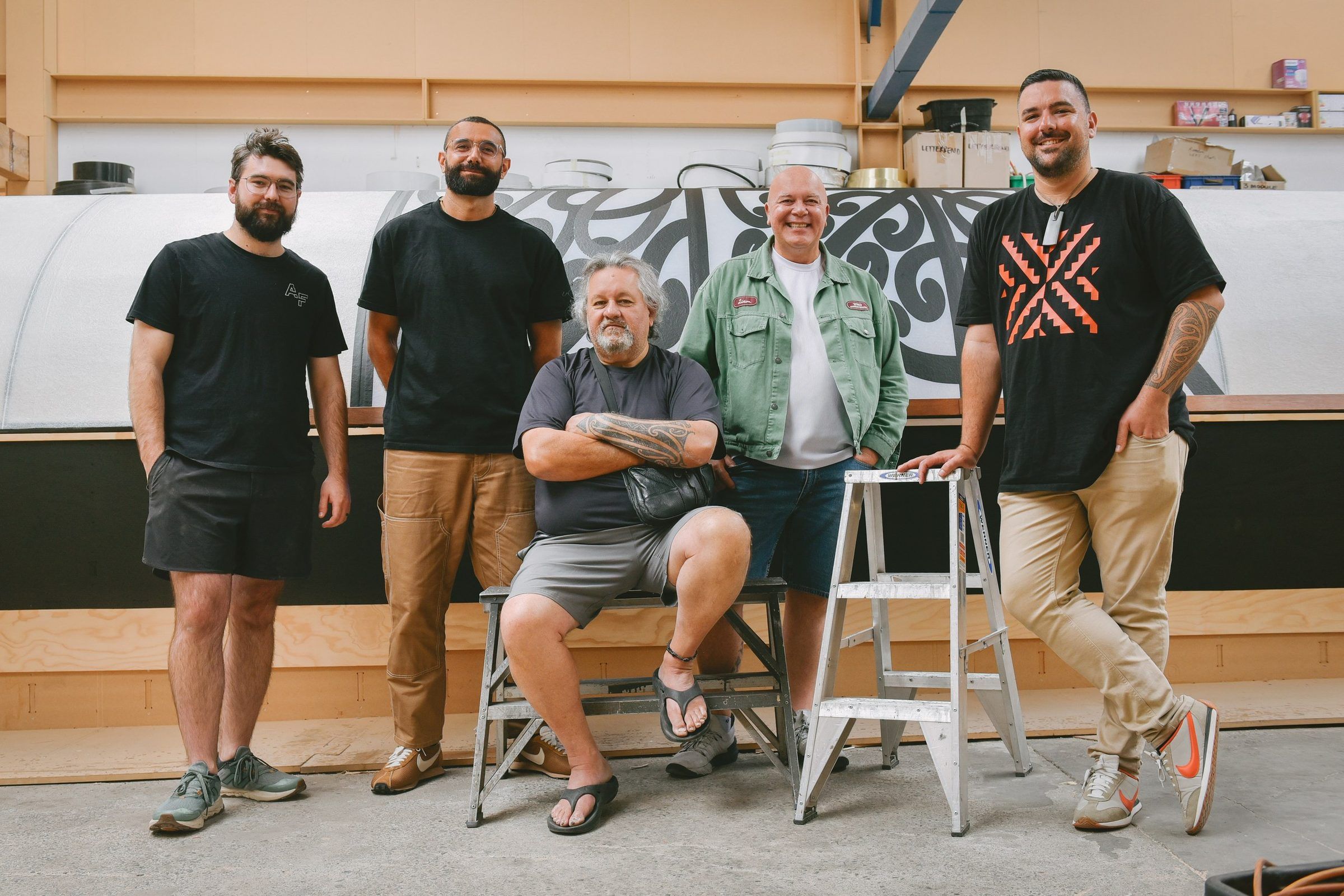 Five makers in front of the waka hull in the workshop