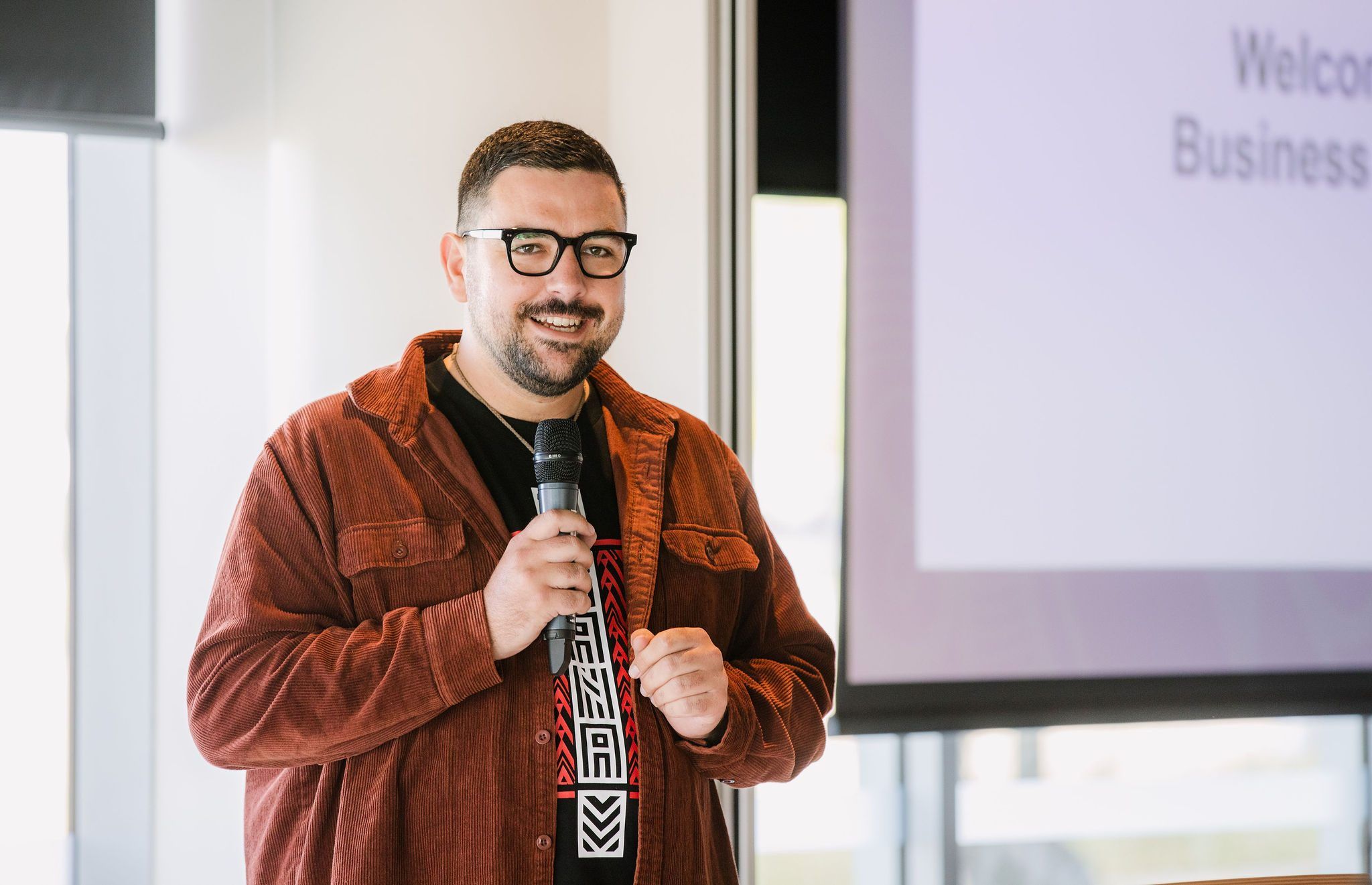 Johny O’Donnell facilitating with a microphone in front of a screen
