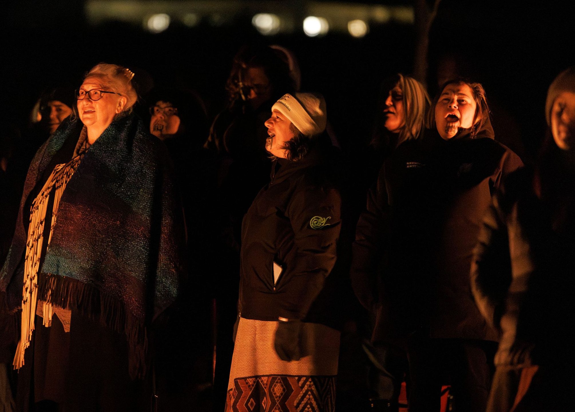Faces lit by firelight at a night-time gathering