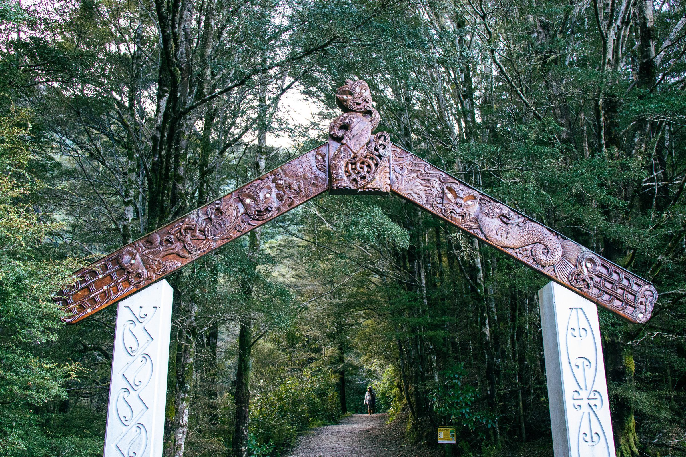 A carved waharoa over a bush track