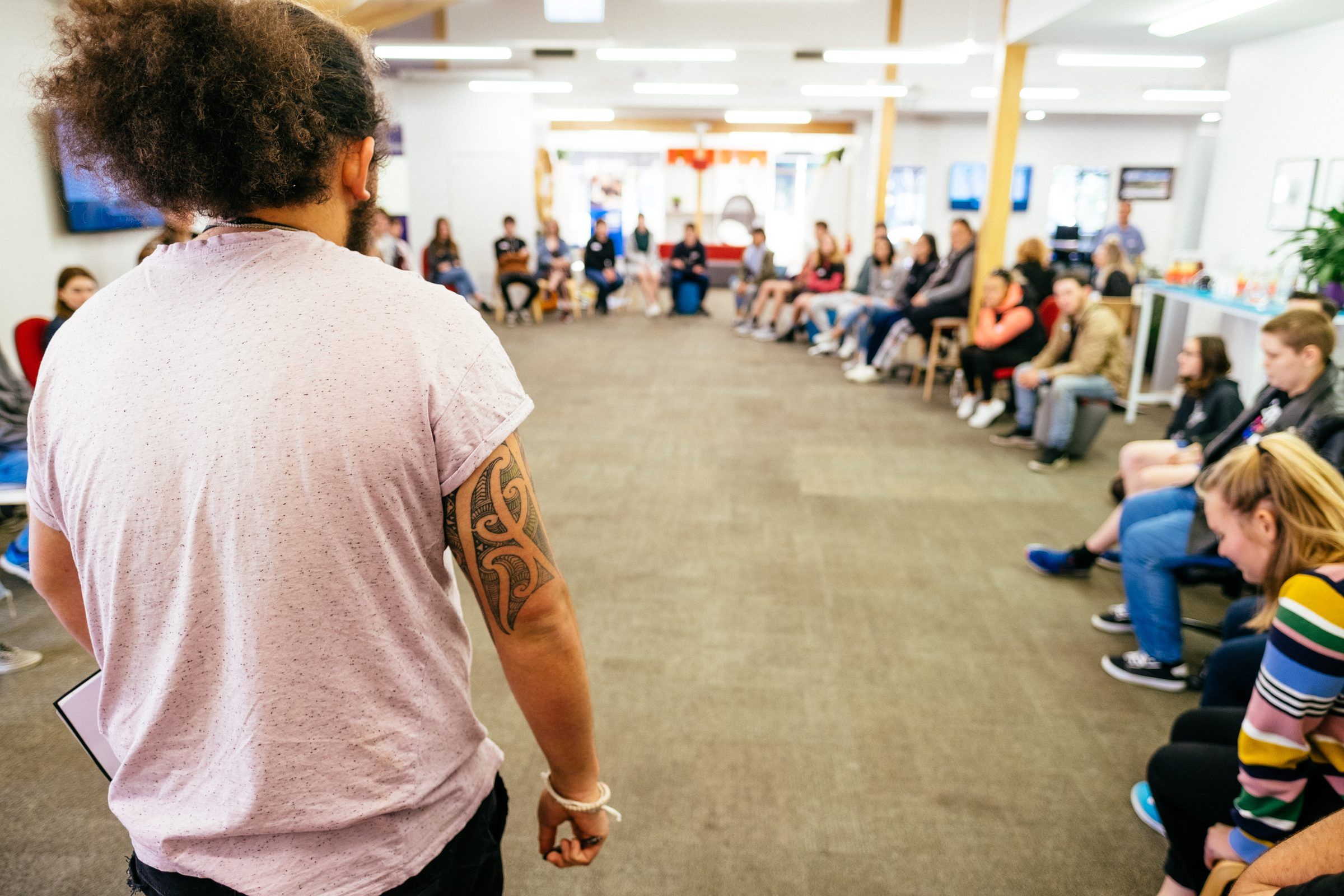Kiwa Denton stands to open the Te Tauihu Youth Summit, rangatahi seated in a wide circle around the room
