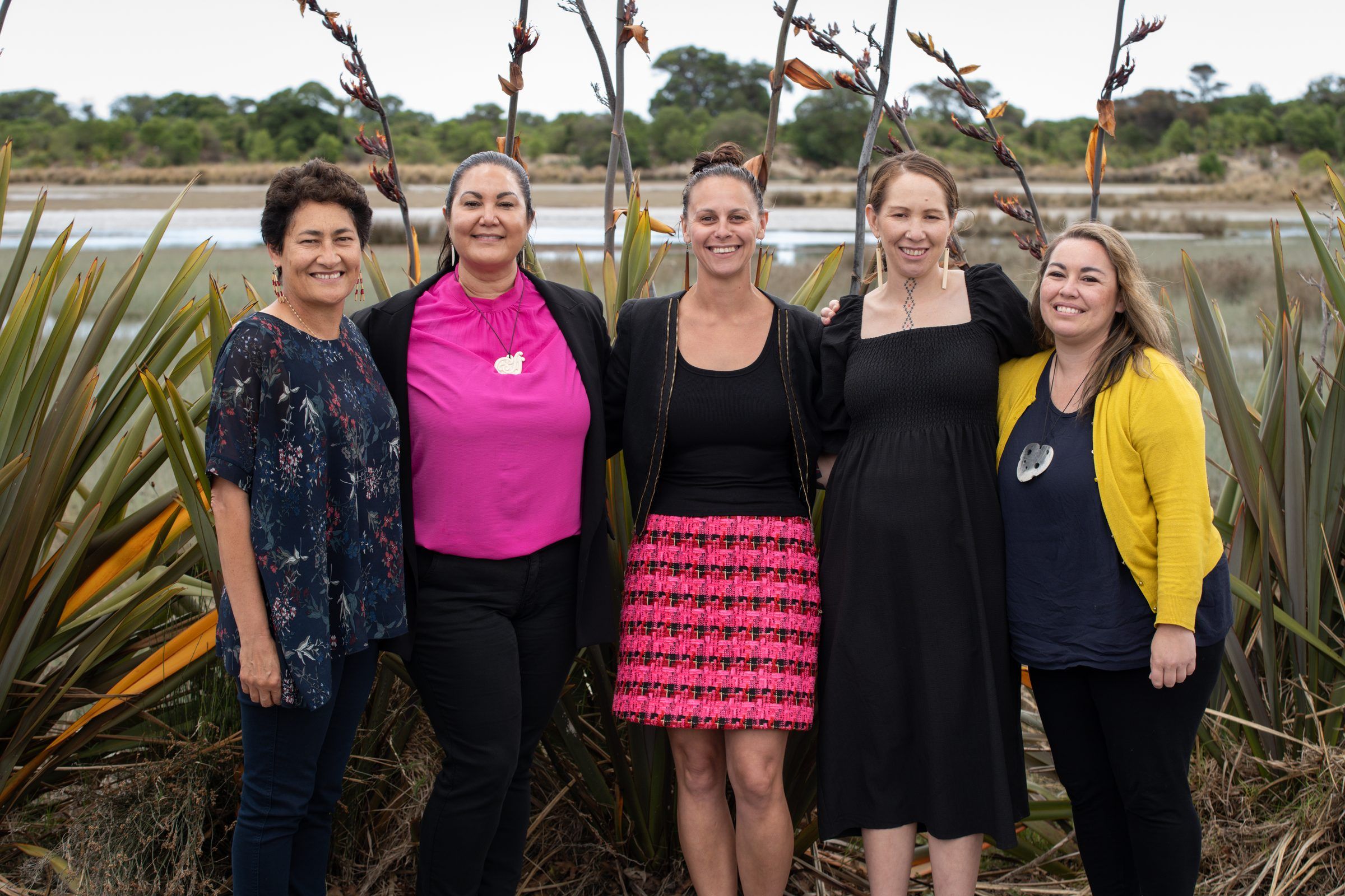 Five women stand together among harakeke on the signing day