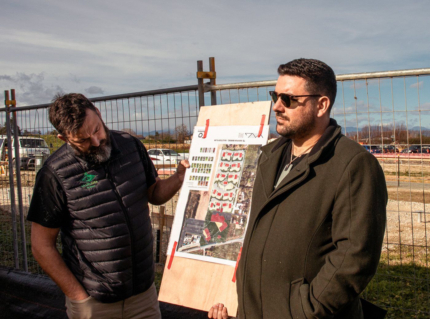 Johny O’Donnell and a site lead review the plans at a construction fence