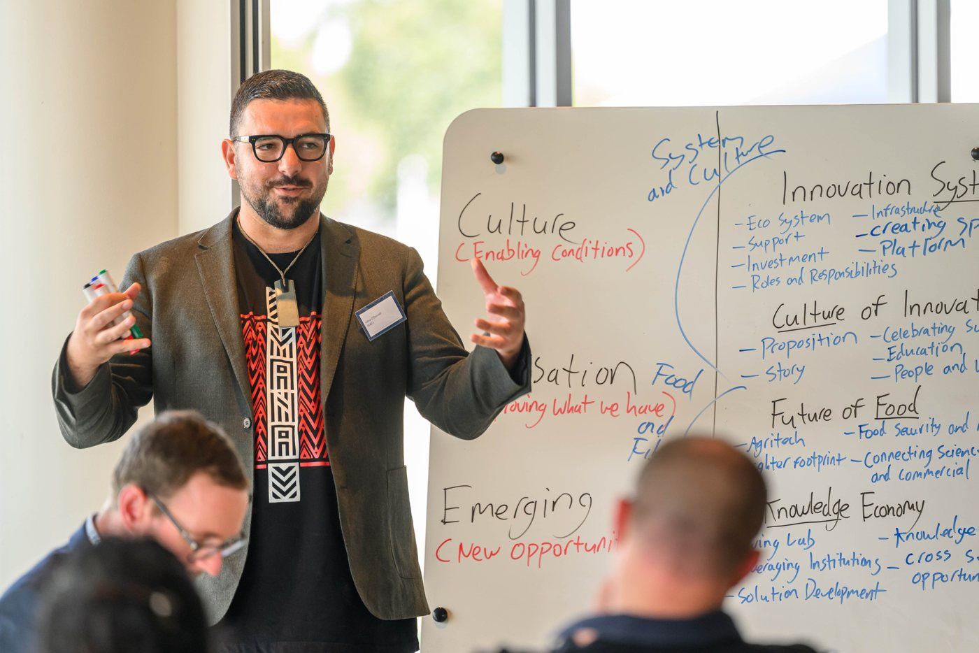 Johny O’Donnell mid-explanation beside a whiteboard of strategy themes